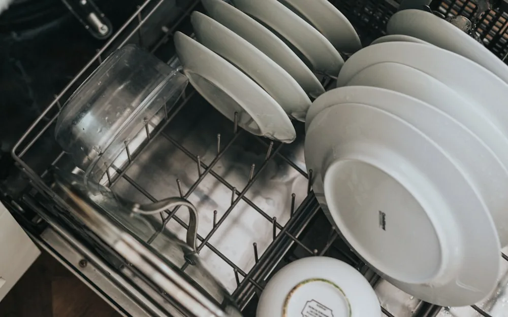 A clean dishwasher interior with neatly stacked white plates.